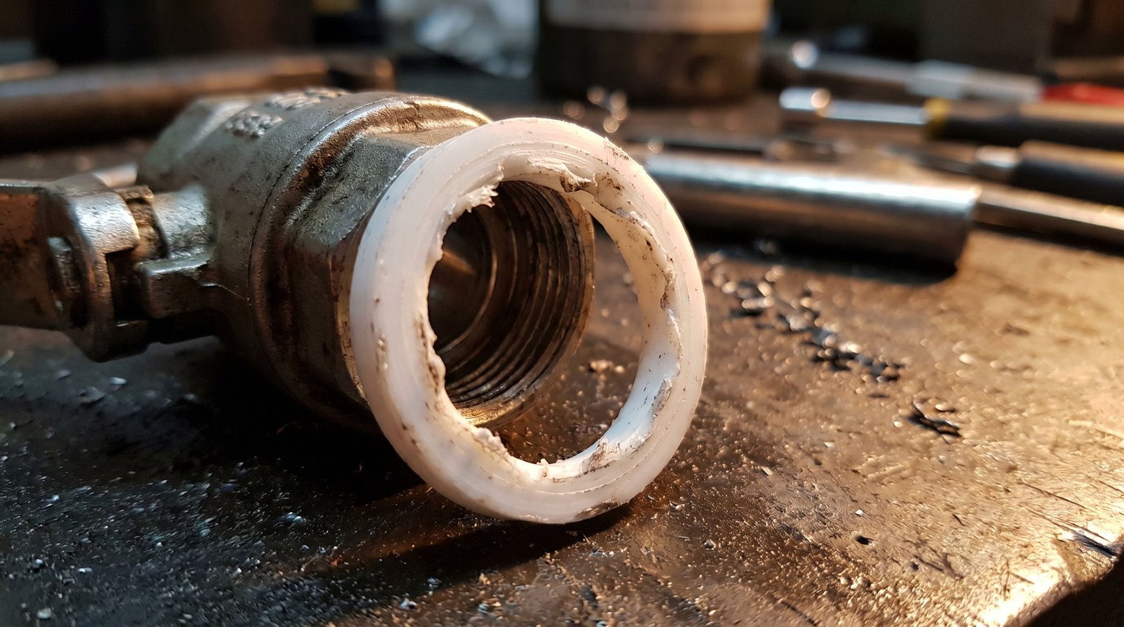 Macro view of a deformed PTFE ball valve seat showing extrusion damage.